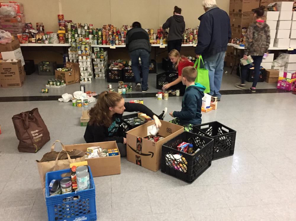 Students help out the local community by sorting and boxing up canned goods for families. 